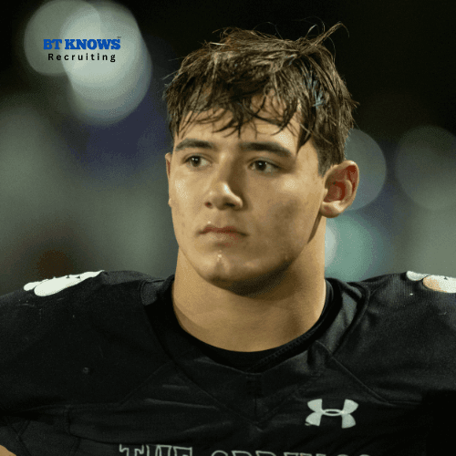 Young football player in uniform looking thoughtful on a dimly lit field.