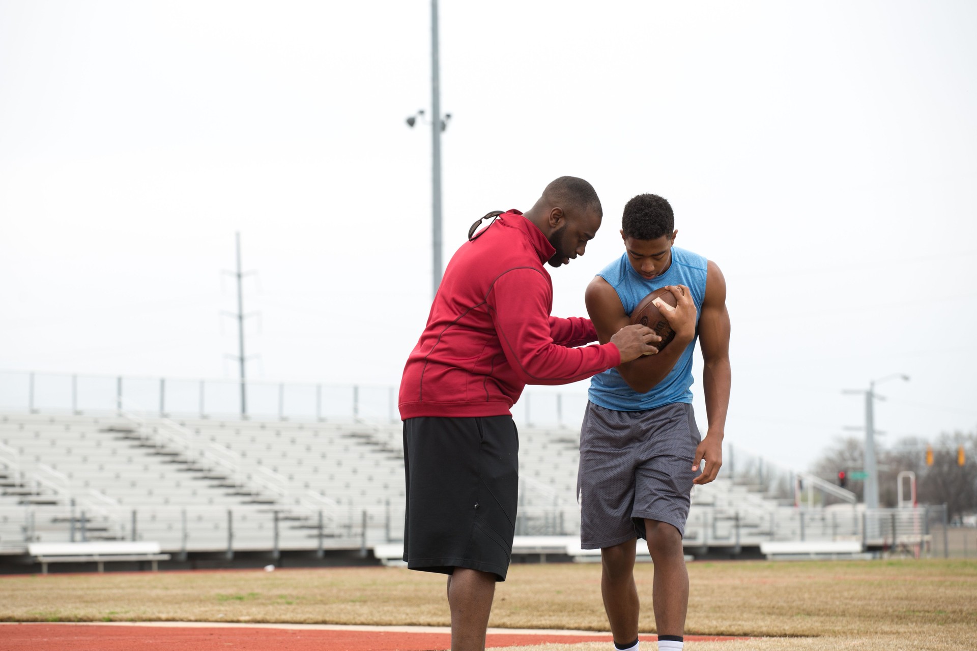 Coach training a high school athlete for football.